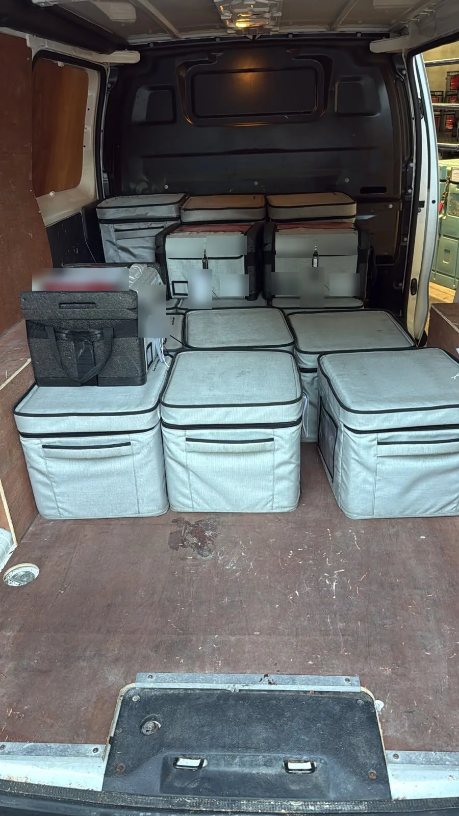 Insulated transport boxes stacked and secured in the back of a Red Eagle Logistics courier van