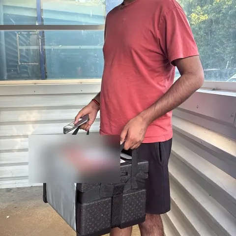 A DBS-checked Red Eagle Logistics courier driver carrying an insulated delivery box